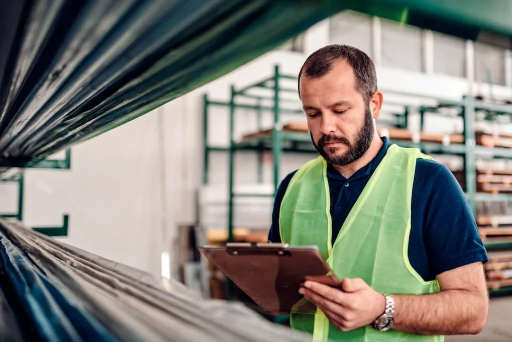 Man in a warehouse checking items wearing a safety vest