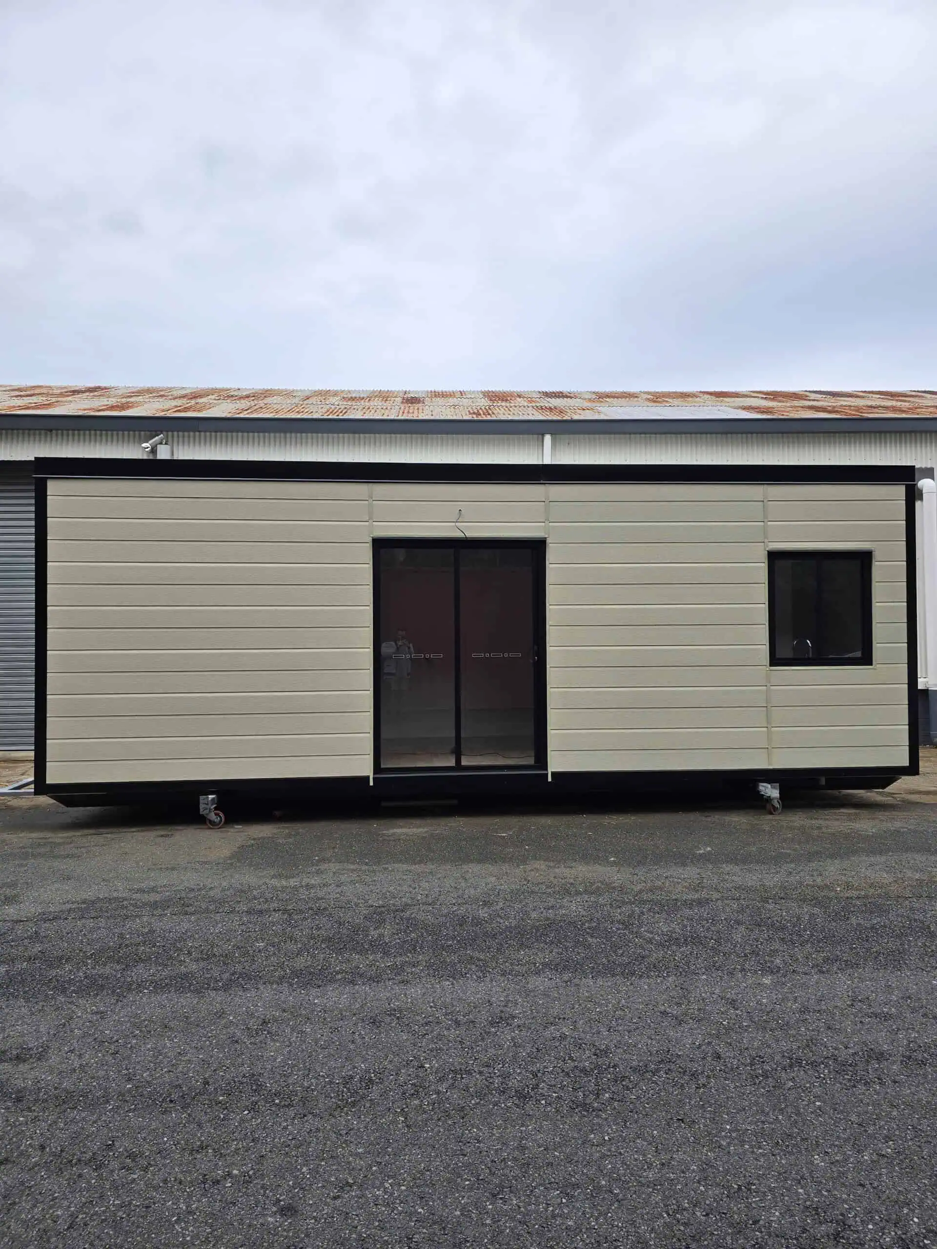 Beige Roomi portable building with black trim and sliding glass door