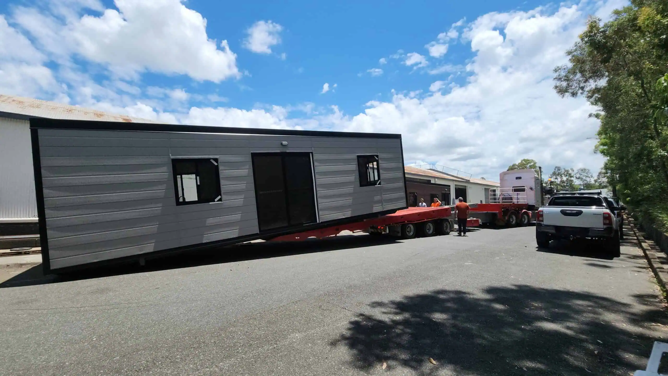 Exterior view of a dark grey Roomi portable building under a blue sky