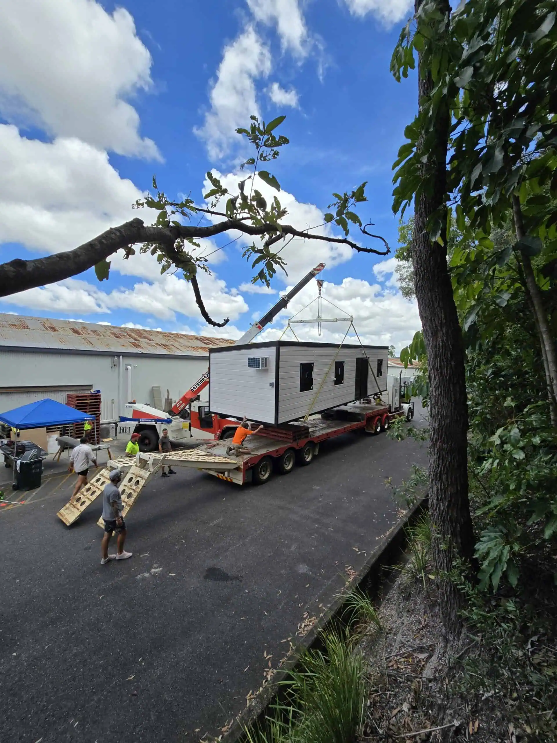 Roomi granny flat being loaded by crane onto a flatbed truck for delivery