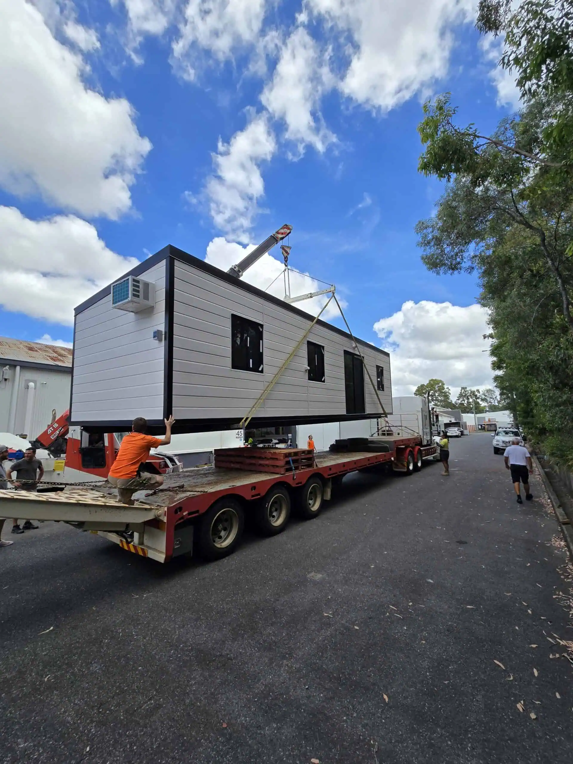 Roomi portable granny flat being lifted by crane onto a delivery truck