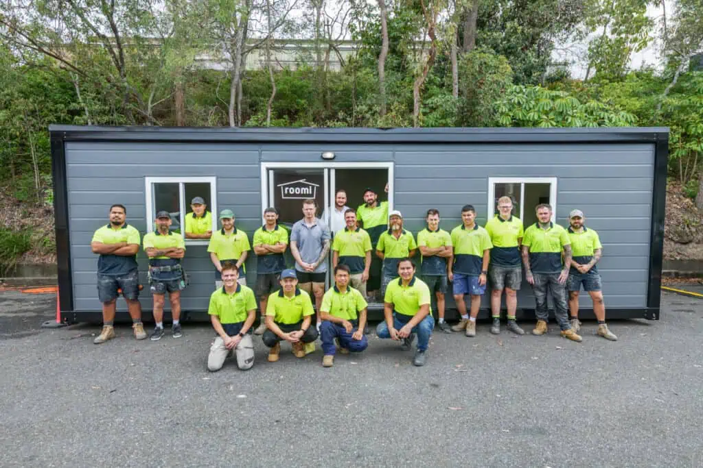 The Roomi team posing in front of one of our transportable buildings